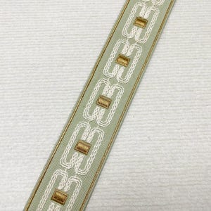 Pode incluir: Uma guarni&ccedil;&atilde;o verde claro com um padr&atilde;o geom&eacute;trico branco e dourado. A guarni&ccedil;&atilde;o tem 2,4 polegadas de largura.