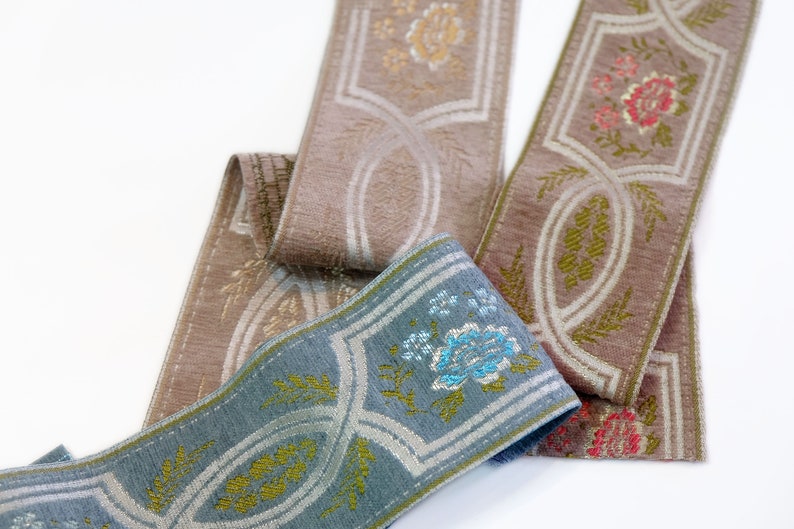 May include: Three different trims of fabric ribbon with floral patterns. The ribbons are in shades of brown, blue, and white.