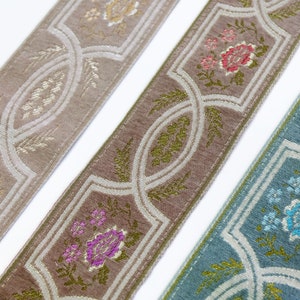 May include: Three different patterned trims with a repeating design of floral motifs and geometric shapes. The trims are in shades of beige, brown, and blue.