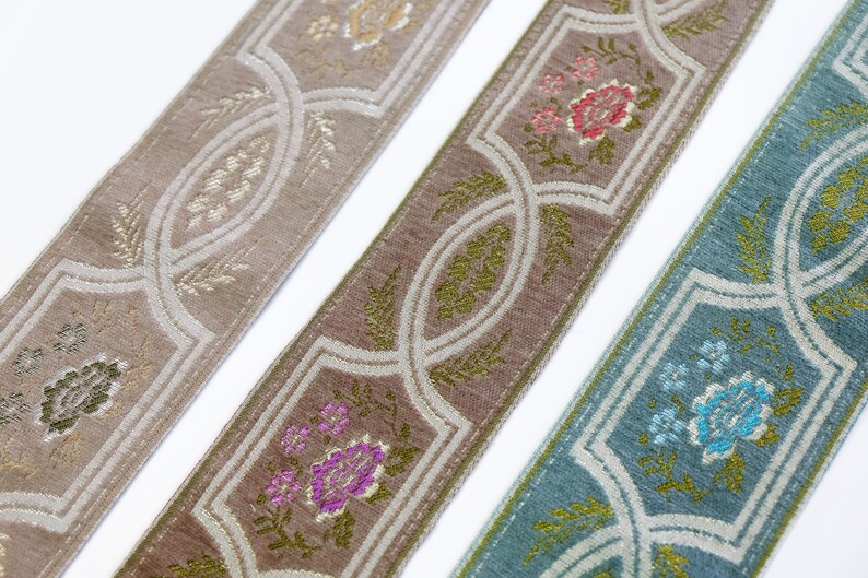 May include: Three different patterned trims with a repeating design of floral motifs and geometric shapes. The trims are in shades of beige, brown, and blue.
