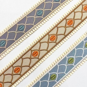 May include: Three different colored trim ribbons with a geometric pattern and a white pom-pom trim. The colors are light blue, beige, and a dark gray.