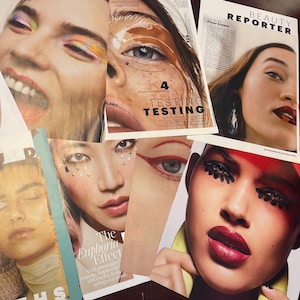May include: A collage of magazine pages featuring different eye makeup looks. The images show various eye shadow colors, eyeliner styles, and false eyelashes. The text on the pages includes "Beauty Reporter", "Finer Liners", and "Testing, Testing, Testing".