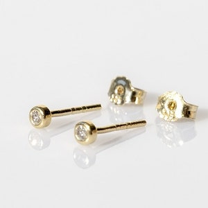 May include: A pair of gold stud earrings with small, clear gemstones.