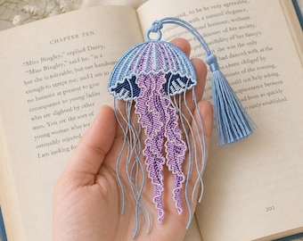 jellyfish bookmark embroidery design with blue tassel in hand over open book, ocean lace machine embroidery file