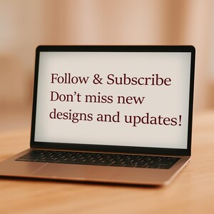 Op de afbeelding: Een opengeklapte laptop met de tekst "Follow & Subscribe Don't miss new designs and updates!". De tekst is donkerrood. De laptop staat op een houten oppervlak.