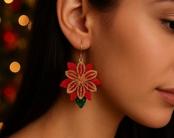 Puede incluir: Pendientes de flor de pascua rojos y dorados con base verde. Los pendientes son de tela y tienen un contorno dorado. Los pendientes cuelgan de un gancho dorado.