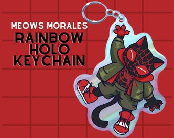May include: A black cat wearing a red and green spider-man costume with a rainbow holographic finish. The keychain features the text "MEOWS MORALES RAINBOW HOLO KEYCHAIN".