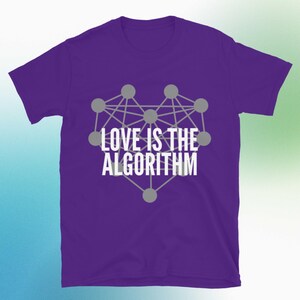 Pode incluir: Uma camiseta roxa com um design gráfico de uma rede em forma de coração com círculos e linhas cinzentas. O texto branco "LOVE IS THE ALGORITHM" está impresso dentro do coração. A camiseta é feita de um material macio.