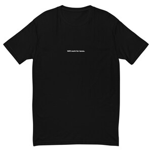 May include: Black t-shirt with the text "Will work for tacos" in white. The shirt has a crew neck and short sleeves. The text is centered on the chest.