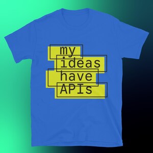 Puede incluir: Una camiseta azul con el texto "my ideas have APIs" en letras negras dentro de rectángulos amarillos. La camiseta está hecha de un material suave y tiene mangas cortas.