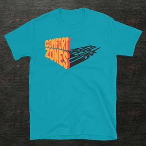 May include: A turquoise blue t-shirt with the text "Comfort Zones" in yellow and red letters with a shadow effect.