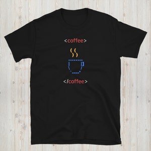 May include: Black t-shirt with a pixelated image of a coffee cup with steam coming out of it. The text '<coffee>' and '</coffee>' is written in red above and below the image.