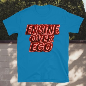 Può includere: Una tazza di ceramica bianca con un manico nero e la scritta "But First, Coffee" in nero, con un carattere a mano. La tazza è su una superficie bianca.