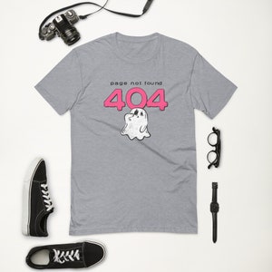 Op de afbeelding: Een heidekleurig t-shirt met een roze 404-foutmelding en een spookafbeelding. De tekst luidt "page not found".