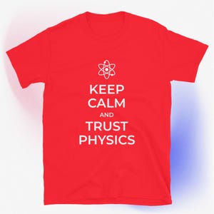 Könnte beinhalten: Rotes T-Shirt mit dem weißen Aufdruck "KEEP CALM AND TRUST PHYSICS" und einem Atomsymbol. Das T-Shirt hat kurze Ärmel und besteht aus einem weichen Material. Das Design ist mittig auf der Vorderseite platziert.