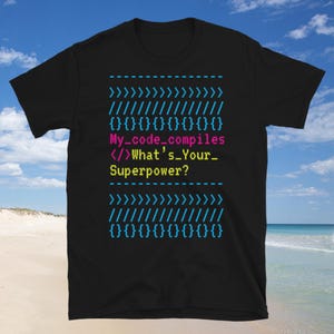 May include: Black t-shirt with a blue and pink code design that reads "{}{}{}{}{}{}{}{} My_code_compiles </>What's_Your_ Superpower? {}{}{}{}{}{}{}{} "