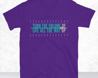 May include: Purple t-shirt with the text "Turn the volume of life all the way up" in teal and grey.