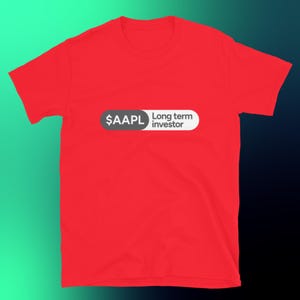 May include: A bright red short-sleeved t-shirt featuring a horizontal pill-shaped graphic on the chest. The left side of the graphic is dark gray with the white text $AAPL, while the right side is white with the black text Long term investor.