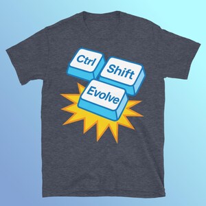 May include: Dark gray t-shirt featuring a graphic of three computer keys: "Ctrl", "Shift", and "Evolve". The keys are light blue with white text, set against a yellow burst design. A casual, tech-themed apparel item.