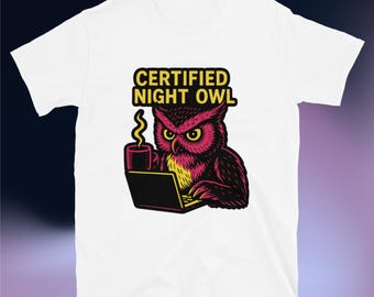 Op de afbeelding: Wit T-shirt met een afbeelding van een uil met gele ogen, een koffiekopje en een laptop. De tekst "CERTIFIED NIGHT OWL" staat boven de uil. De uil is in tinten rood, zwart en geel.
