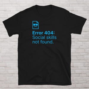 May include: Black t-shirt with a blue graphic of a file icon with a sad face and sunglasses. The text "Error 404: Social skills not found." is printed below the icon.