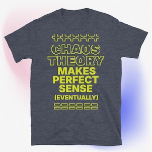 May include: A dark heather grey t-shirt with a yellow pixelated graphic that reads "Chaos Theory Makes Perfect Sense (Eventually)".