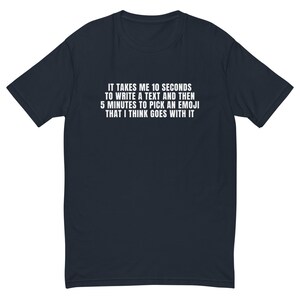 May include: A dark blue t-shirt with white text that reads "IT TAKES ME 10 SECONDS TO WRITE A TEXT AND THEN 5 MINUTES TO PICK AN EMOJI THAT I THINK GOES WITH IT".