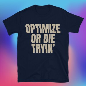 May include: Navy blue t-shirt with the text "OPTIMIZE OR DIE TRYIN'" in a distressed, light tan font. The graphic is centered on the front of the shirt. The shirt has short sleeves and a crew neck.