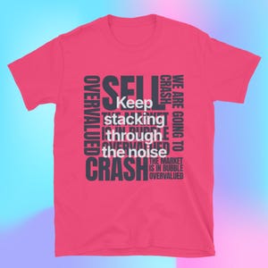 Könnte beinhalten: Ein kurzärmeliges, pinkfarbenes T-Shirt mit einem dunkelgrauen Grafikdesign. Das Design zeigt die Wörter "SELL", "CRASH", "OVERVALUED" und "WE ARE GOING TO" sowie die Sätze "Keep stacking through the noise" und "The market is in bubble, overvalued."