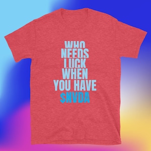 Pode incluir: Camiseta vermelha com o texto azul claro: « WHO NEEDS LUCK WHEN YOU HAVE SNVDA ». O texto está empilhado verticalmente, com « SNVDA » na parte inferior.