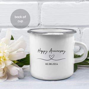 May include: White enamel mug with a silver rim. The mug has a black handwritten inscription that says "Happy Anniversary" with a heart symbol and the date "02.08.2014".