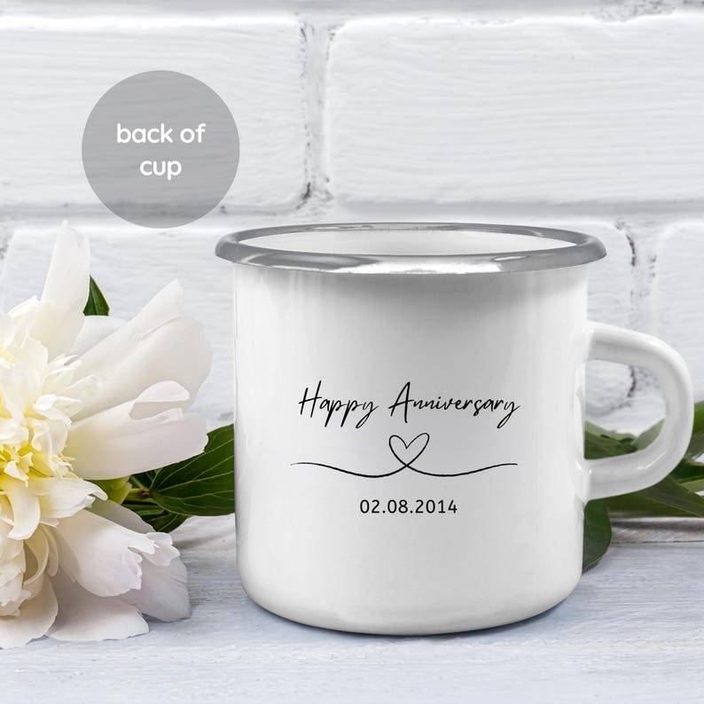 May include: White enamel mug with a silver rim. The mug has a black handwritten inscription that says "Happy Anniversary" with a heart symbol and the date "02.08.2014".