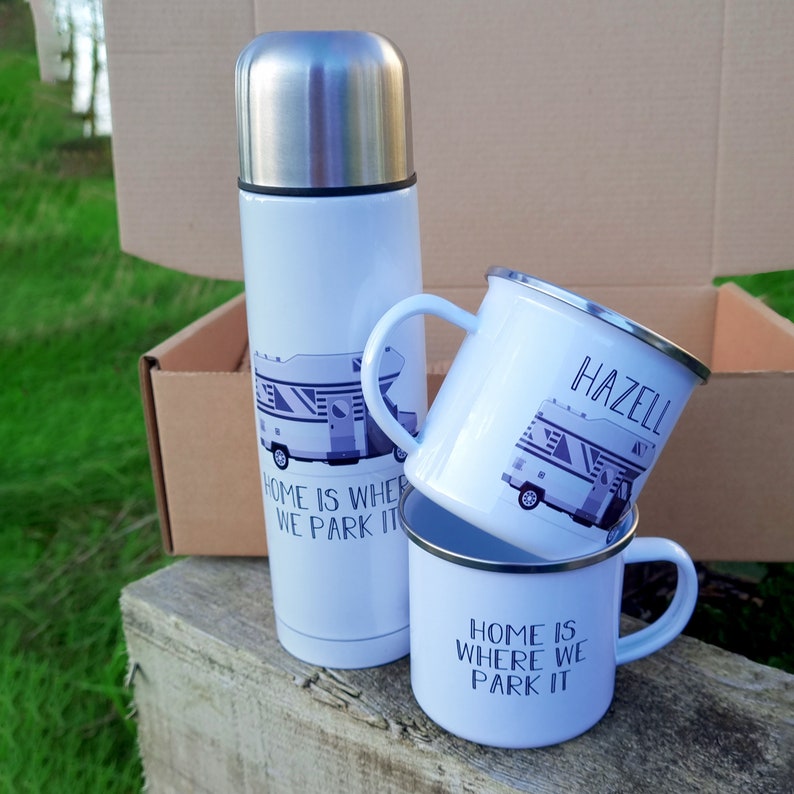 May include: White insulated travel mug with a camper van graphic and the text "Home is where we park it".  Two white enamel mugs with the same graphic and text, one with the name "Hazell" on it.