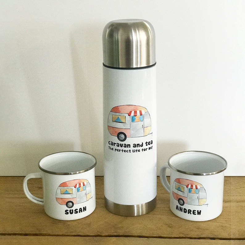May include: Two white enamel mugs with a cartoon caravan design and the names "Susan" and "Andrew" printed on them. A white stainless steel thermos with a cartoon caravan design and the text "caravan and tea the perfect life for me!" printed on it.