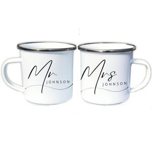 May include: Two white enamel mugs with black lettering. The mug on the left says "Mr. JOHNSON" and the mug on the right says "Mrs. JOHNSON".