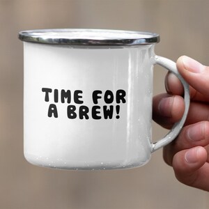 May include: White enamel mug with a black inscription that reads "TIME FOR A BREW!" The mug has a silver rim and handle.