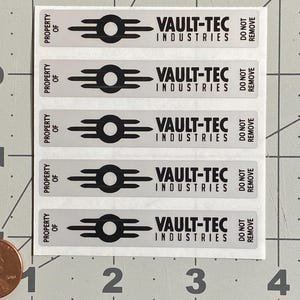 May include: A sheet of rectangular stickers with the Vault-Tec Industries logo. Each sticker is light gray with black text and a black logo. The text reads "PROPERTY OF", "VAULT-TEC INDUSTRIES", and "DO NOT REMOVE".