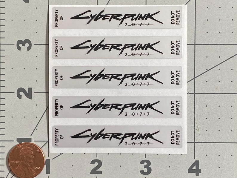 May include: A sheet of rectangular stickers with the word "Cyberpunk" in a stylized font, along with the numbers "2077". Each sticker also has the text "Property of" and "Do Not Remove". The stickers are on a white background.