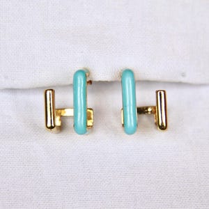 May include: A pair of gold earrings with turquoise blue rectangular accents.