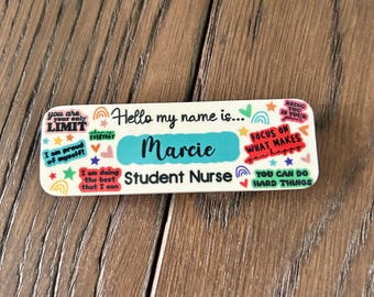 May include: White name tag with colorful stickers and the text "Hello my name is... Marcie Student Nurse".