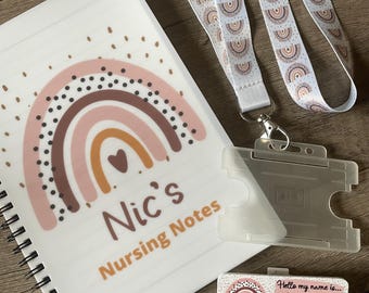 May include: A white spiral notebook with a pink, brown, and orange rainbow design. The notebook says "Nic's Nursing Notes". A white lanyard with a rainbow pattern is included, along with a clear plastic ID badge holder. A small card with a rainbow design says "Hello my name is... Nicole Student Learning Disability Nurse".