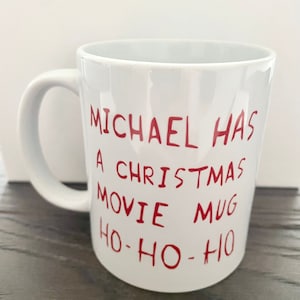 May include: White ceramic mug with red text that reads "Michael has a Christmas movie mug ho-ho-ho".