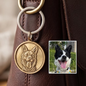 Pode incluir: Uma bolsa de couro castanho com uma medalha dourada para cães. A medalha apresenta um relevo detalhado do rosto de um cão. Uma pequena foto de um cão preto e branco também é visível.