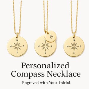 Könnte beinhalten: Goldfarbene Kompass-Halsketten mit Kette. Die Windrose ist auf einem runden Anhänger eingraviert. Eine Halskette hat einen kleineren Anhänger mit dem Buchstaben "A". Der Text lautet "Personalized Compass Necklace Engraved with Your Initial."