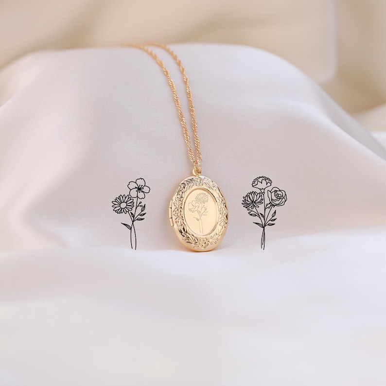 May include: A gold chain necklace with a gold oval locket featuring a delicate floral design. The locket is engraved with a single flower.