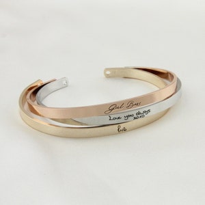 May include: A gold, silver, and rose gold bangle bracelet with the inscription "Girl Boss" and "Love you always xoxo" in cursive handwriting.