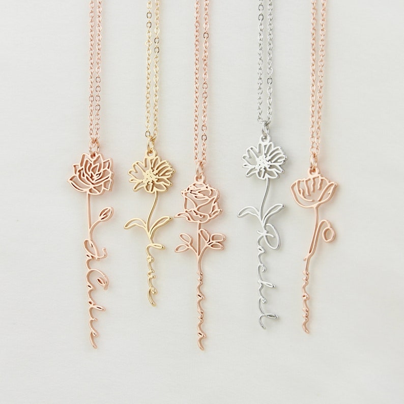 May include: Five delicate gold, silver, and rose gold necklaces with flower pendants. Each pendant features a different flower design and a name inscribed on the stem. The names are "Love", "Dream", "Faith", "Believe", and "Hope".