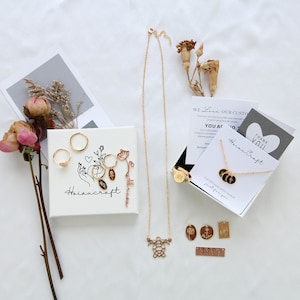 May include: A set of gold jewellery with a delicate chain necklace, a turtle pendant, and a variety of charms. The jewellery is displayed on a white surface with a small white box that says "Hoiancraft" and a card that says "We Love Our Customers".