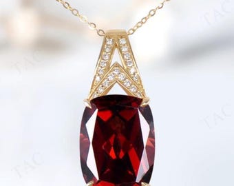 May include: A gold pendant necklace featuring a large, rectangular, deep red gemstone. The pendant is suspended from a delicate gold chain. The top of the pendant has a gold design with small, clear gemstones.