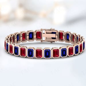 May include: A gold bracelet with alternating red and blue rectangular gemstones. The bracelet has a clasp closure.